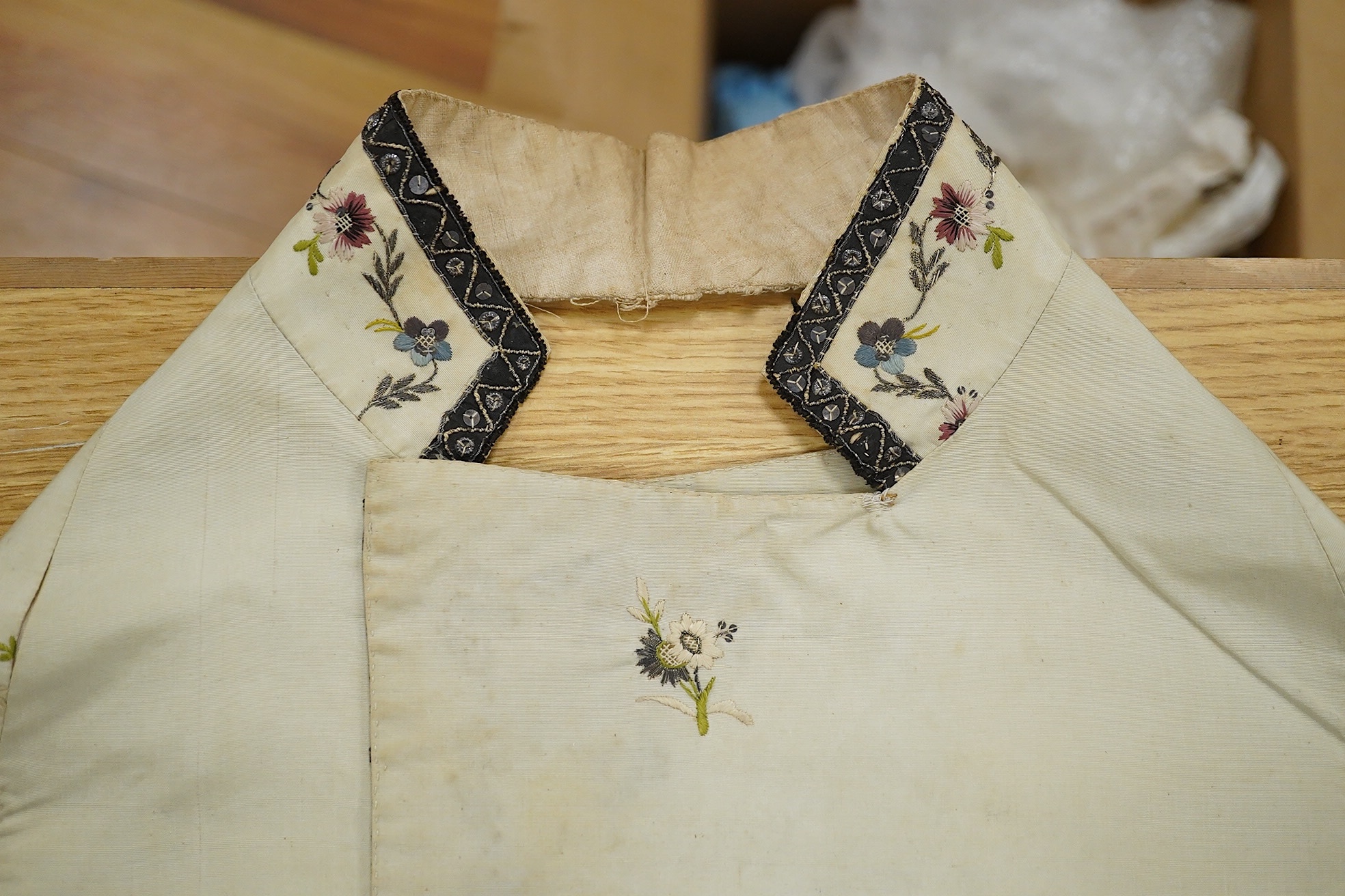 A late George III / George IV gentleman’s cream silk embroidered and cut steel waistcoat front, finely embroidered with polychrome flowers and cut steel appliqués on wide lapels, panel fronts and stand up collar, edged w